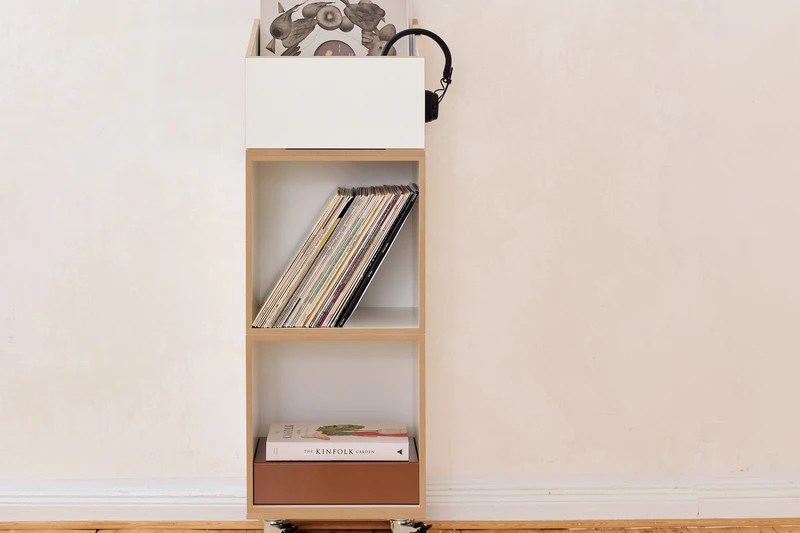 A small stocubo rolling unit with three compartments holding records, headphones and books