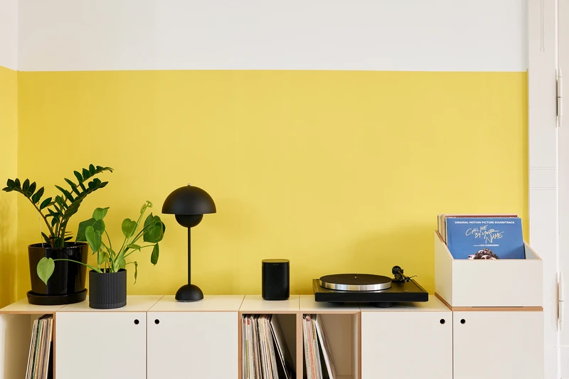 A wide stocubo lowboard with a turntable, amplifier and records on a dark wall