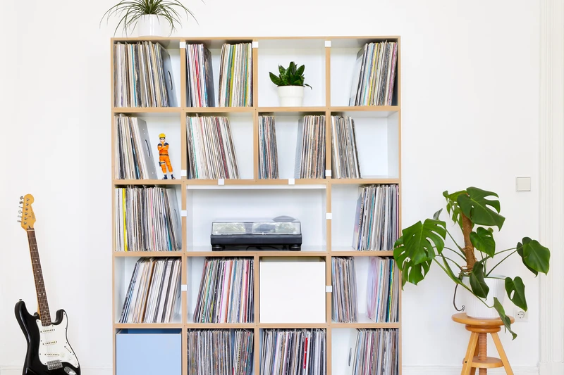 A large floor-to-ceiling stocubo shelving wall with twenty compartments packed with records